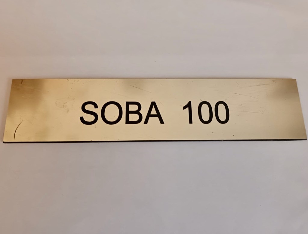 A hotel room plaque: 'Soba 100'.